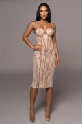 Woman wearing a beige dress with a subtle pattern on a gray background